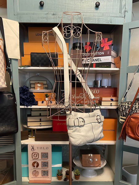 Coach Convertible Midi leather shoulder bag hanging in a handbag display