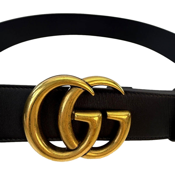 Close-up of the antique gold-tone Double G buckle on the Gucci GG Marmont black leather belt